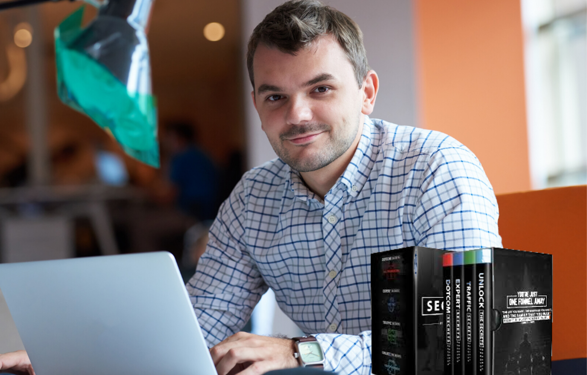 man sitting in front of a computer with clickfunnel triliogy books beside him